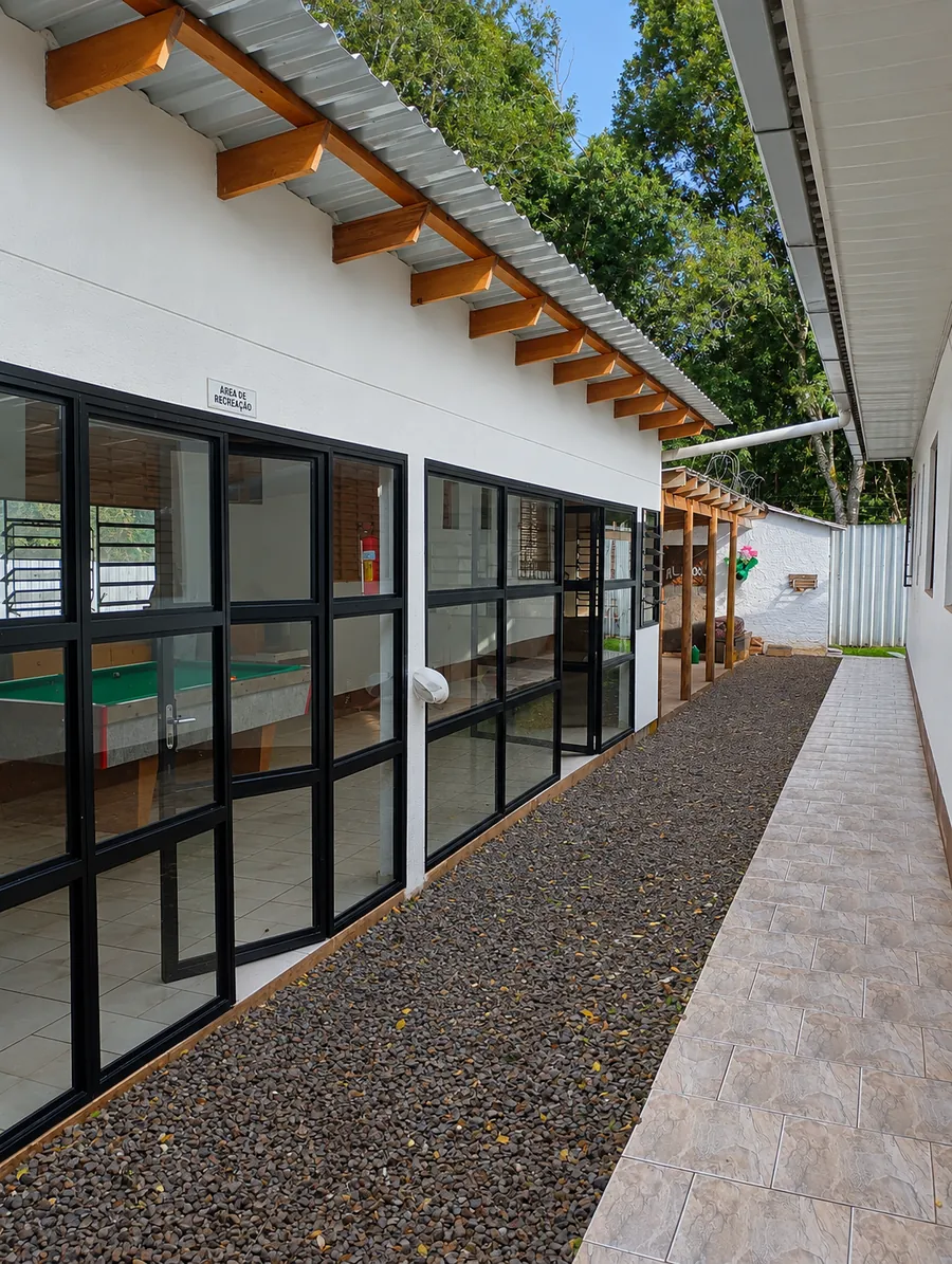 Sala de recreação com mesa de sinuca e janelas amplas voltadas para o jardim