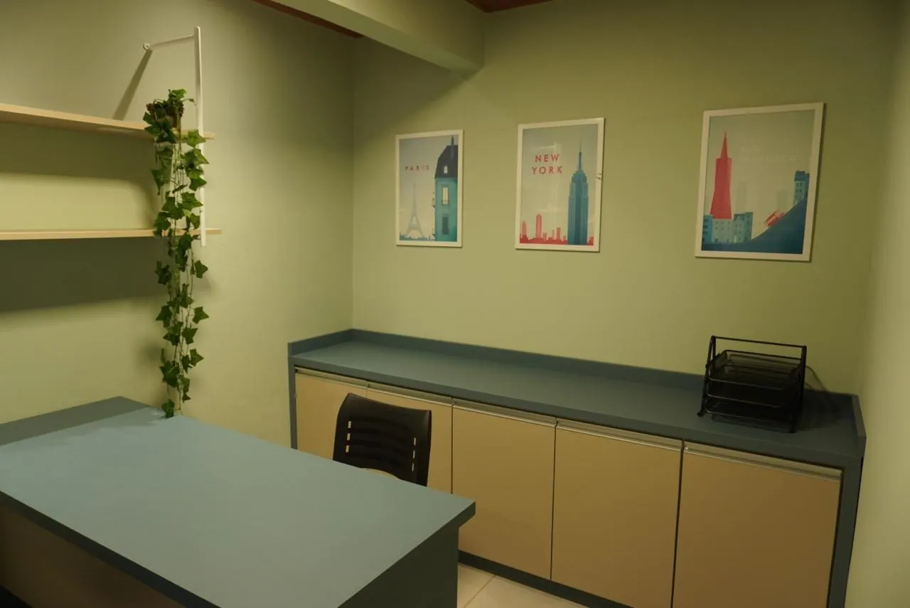 Sala de atendimento com mesa, armários e quadros na parede